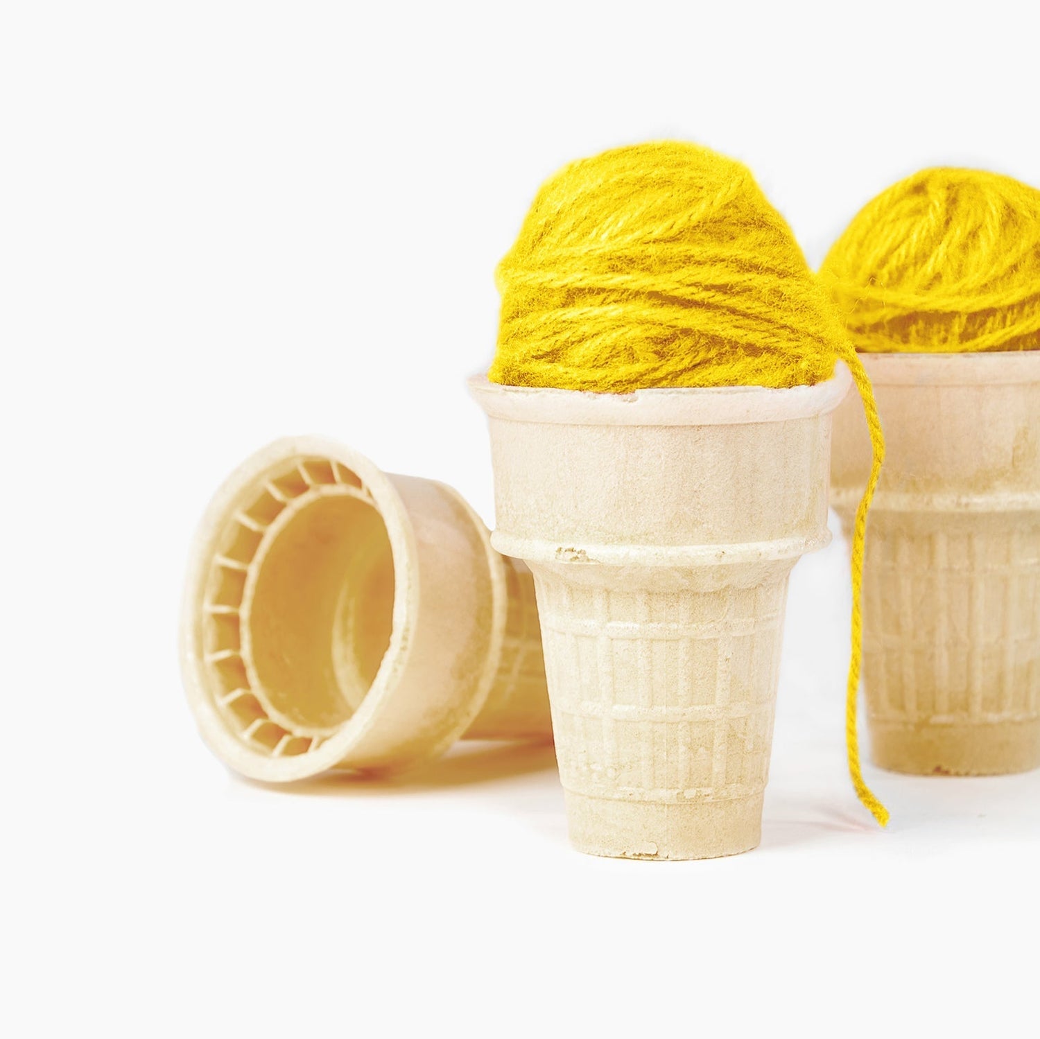 Zwei gelbe Wollknäuel als "Eiskugeln" in Eiswaffeln
